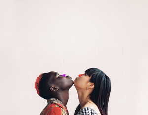 Models facing each other, looking up with chins pressed together wearing nöz reef safe, colorful sunscreen on their noses.